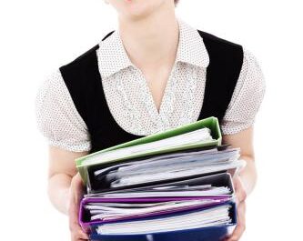 A stressed woman holding binders.