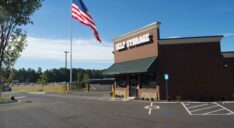 The exterior of the leasing office at Premier Storage shows customer parking and the facility access gate.