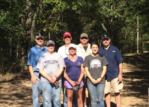 Team of ASM employees smiling for a photo in the woods.