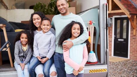 Happy family sitting on the back of a moving truck.