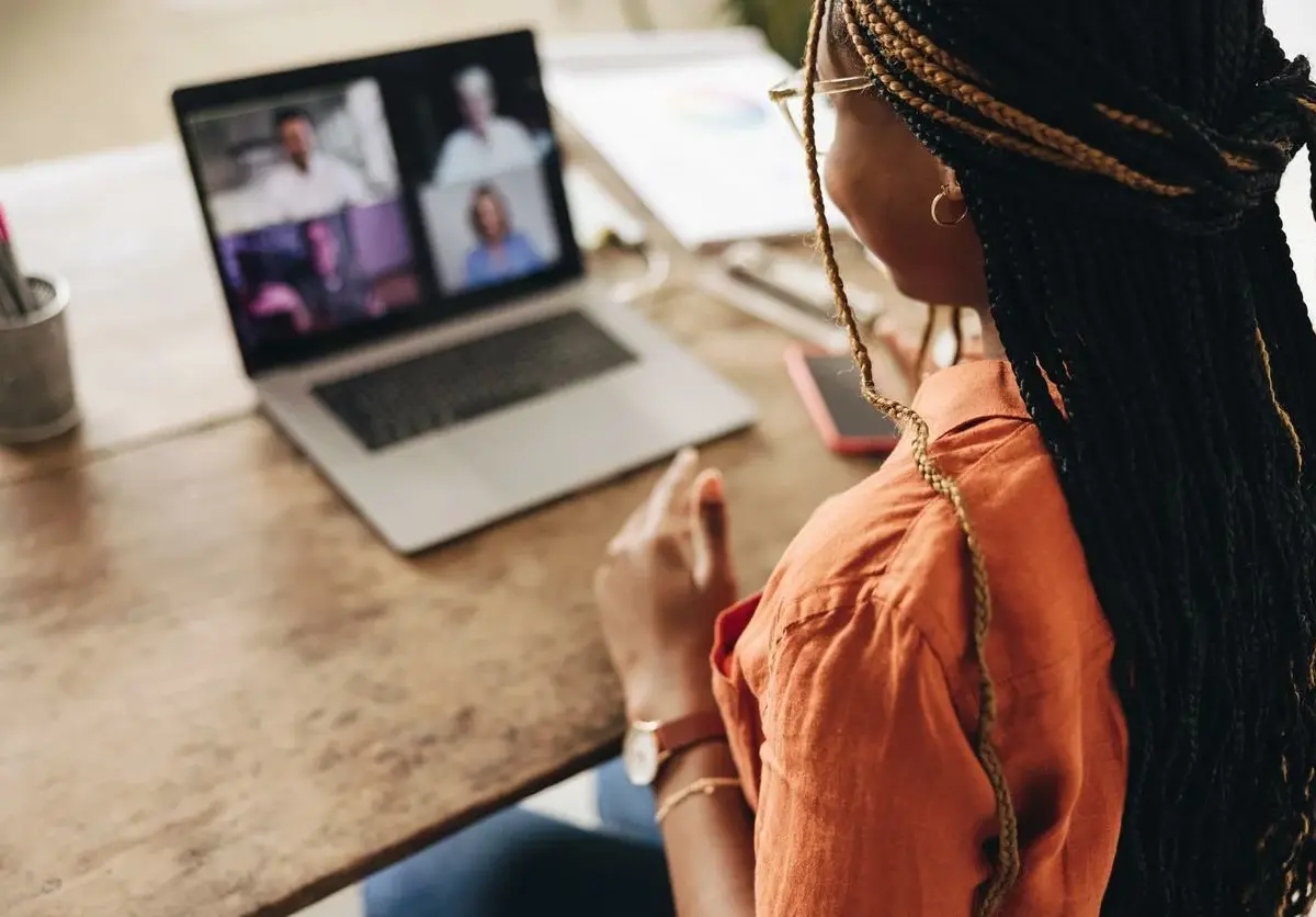 A woman sits and speaks to a screen during a video call