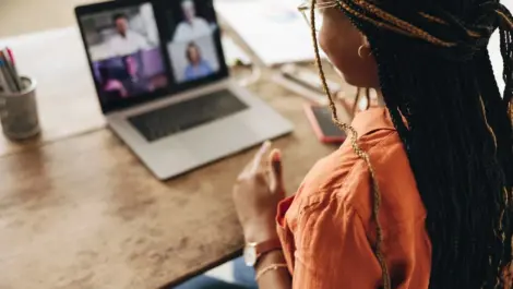 A woman sits and speaks to a screen during a video call