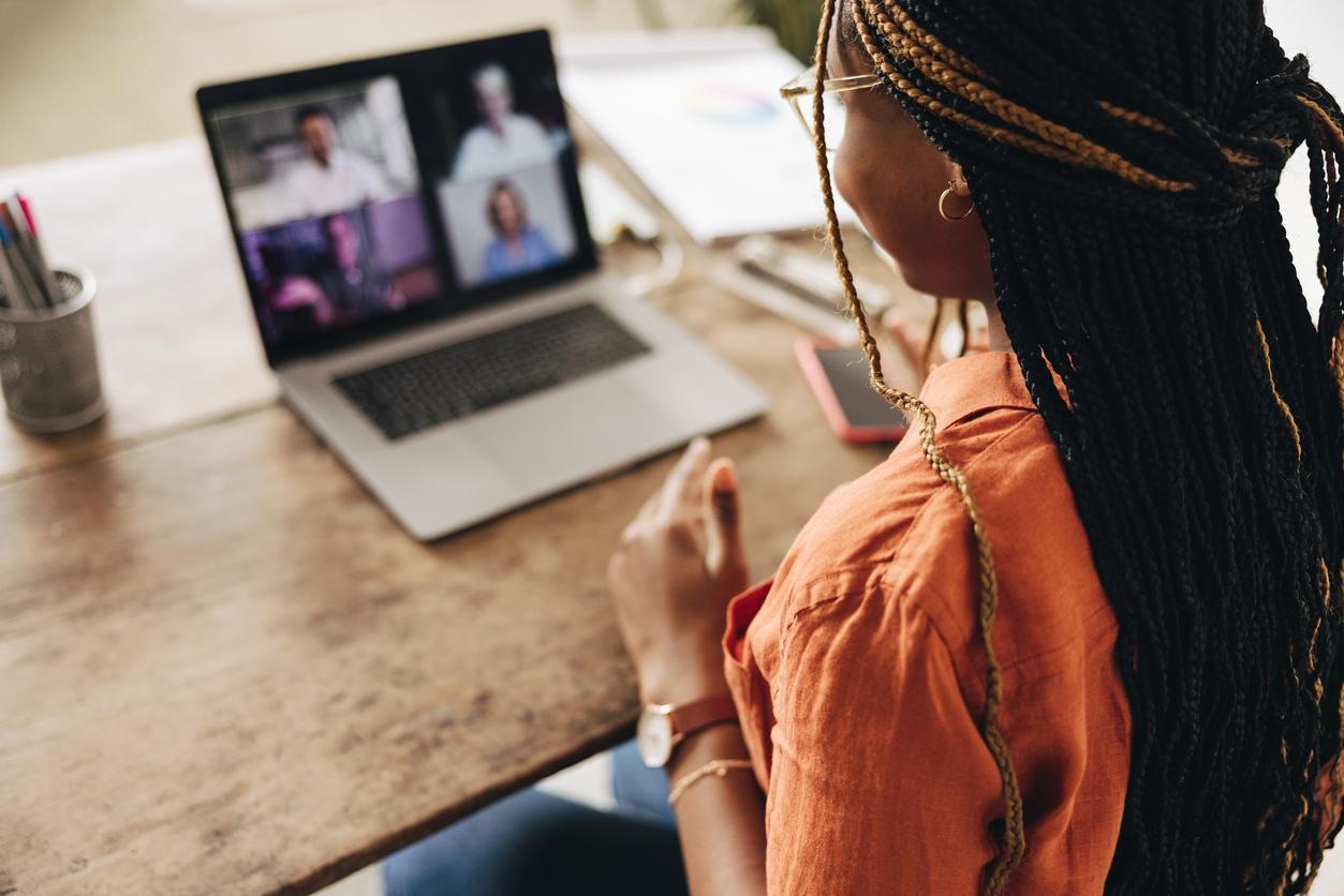 A woman sits and speaks to a screen during a video call