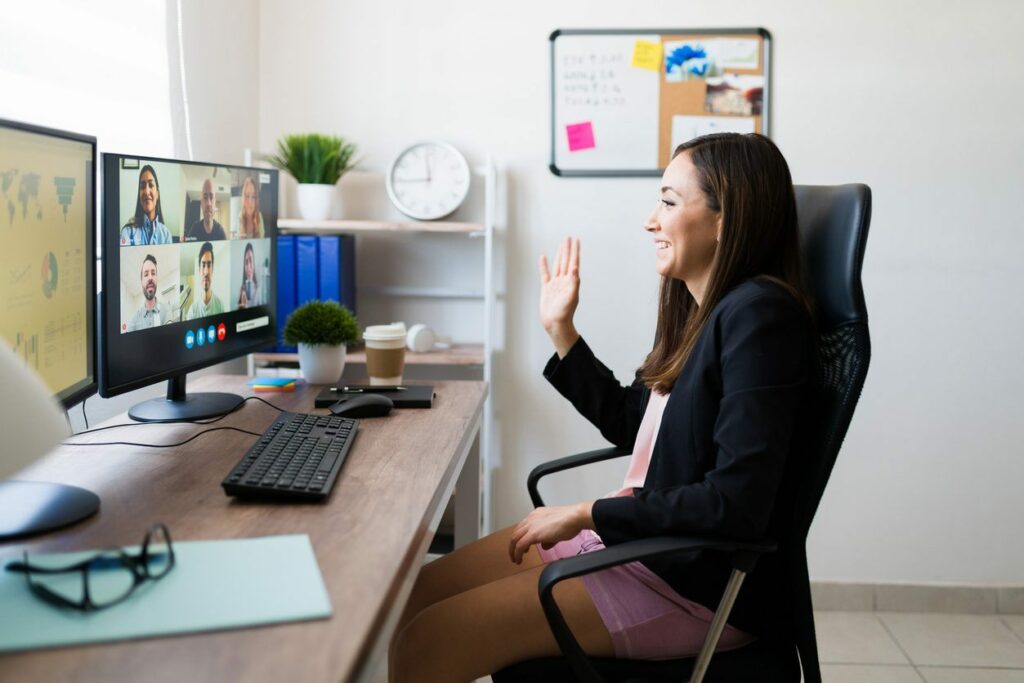 A woman sits at a desk at home on a video call