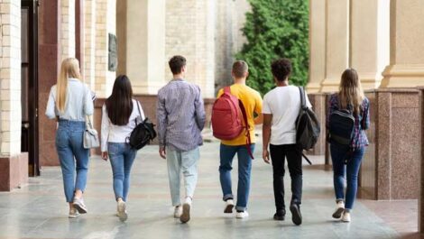 group of students with backpacks walking across campus