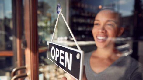 woman turning a business's window sign from open to closed