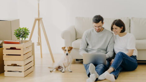 Happy couple using a computer while packing or unpacking their apartment.