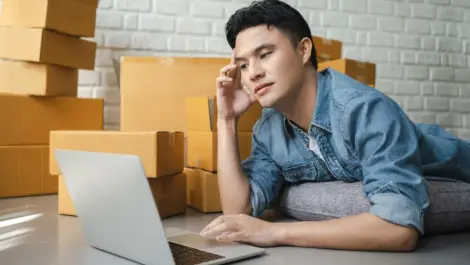 Person working on laptop surrounded by cardboard boxes