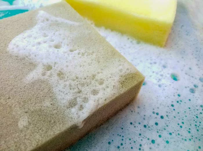 Two yellow and gray sponge cleaning foams with bubbles.