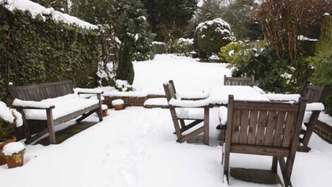 Suburban snow covered patio with garden furniture.