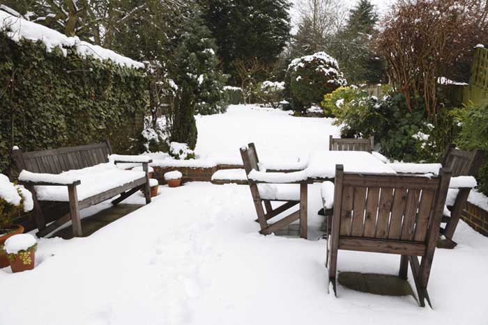 Suburban snow covered patio with garden furniture.