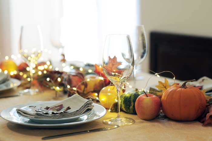 A table decorated for Thanksgiving with leaves, gourds, and small lights.