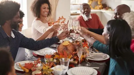 Multi generation mixed race family raise their glasses to make a toast at Thanksgiving