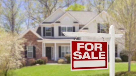 For sale sign in front yard of a house.