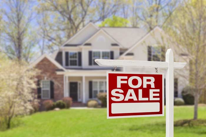 For sale sign in front yard of a house.