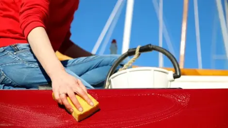 A person washing a red boat with water and soap