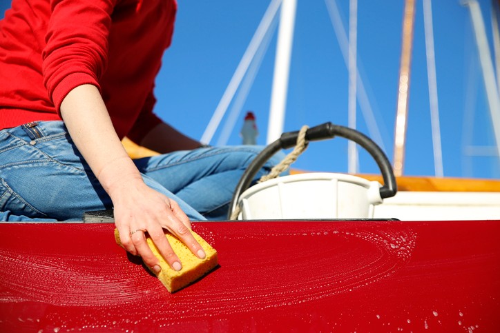 A person washing a red boat with water and soap
