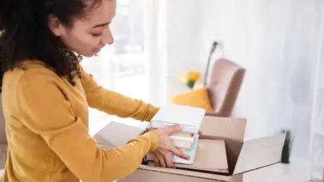 A woman placing books into a cardboard box
