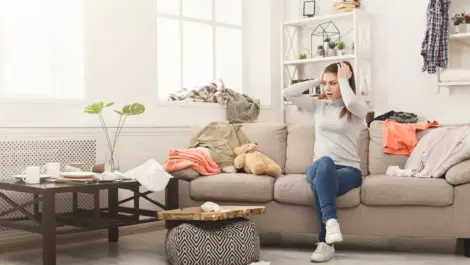 A woman sits on a couch grabbing her head looking stressed out