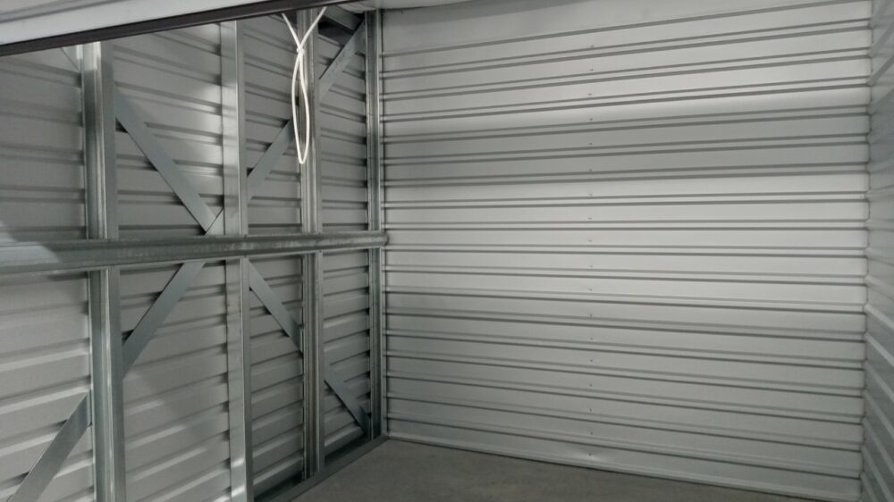 Inside of a clean, medium sized storage unit with a roll-up door.