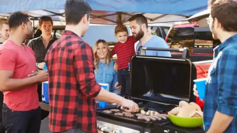 A group of friends gather around a grill to celebrate together