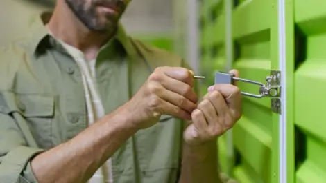 A man uses a key to unlock a storage unit with a bright green door