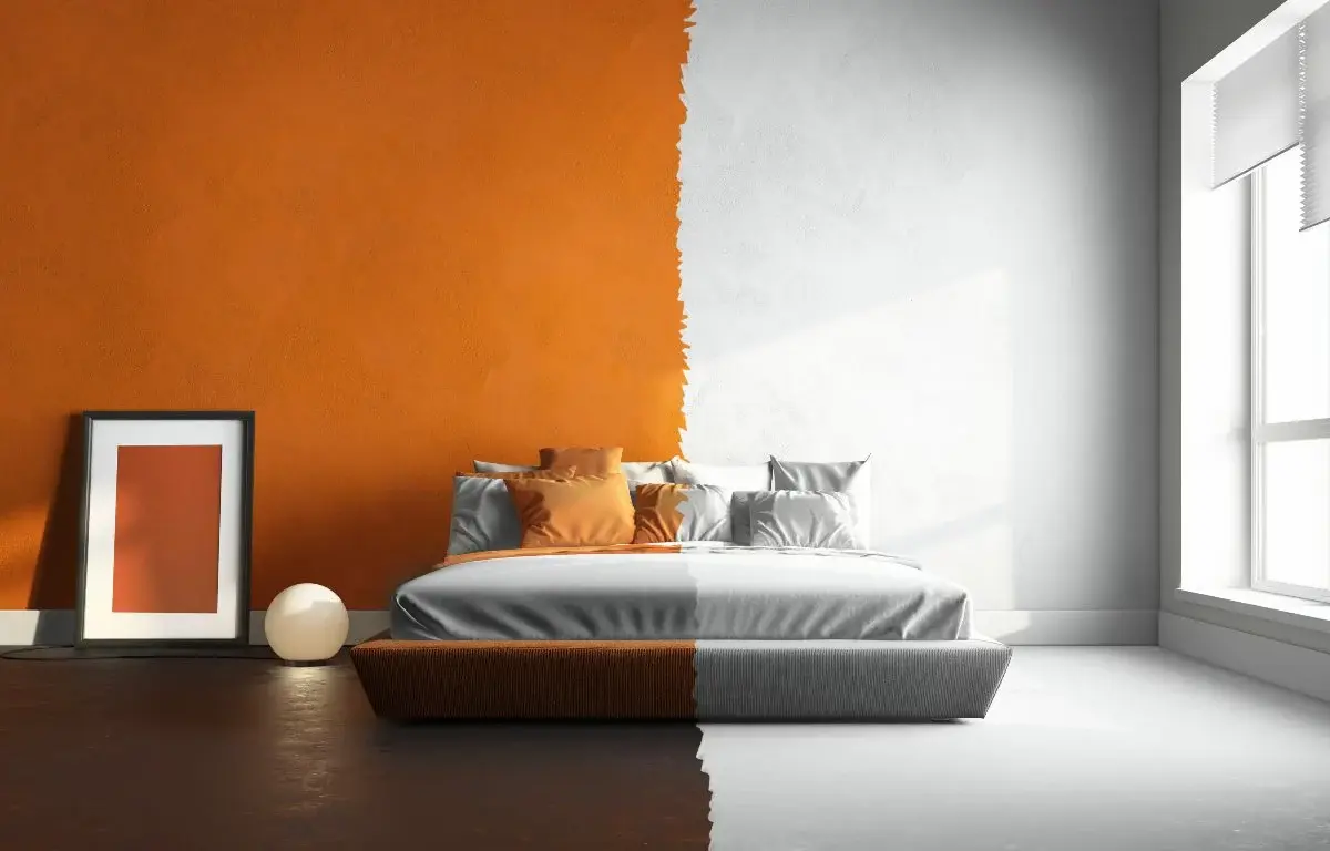 A bedroom with one-half orange walls, dark flooring, and extra décor and one-half white walls, white bedding, and floors with no extra décor