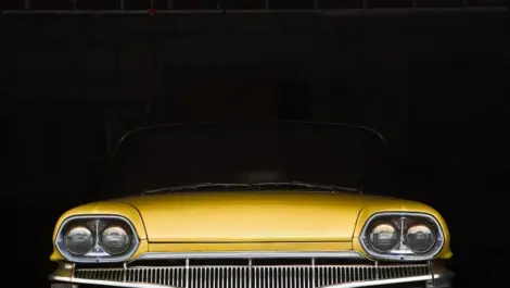A yellow classic car sits in a dark storage unit