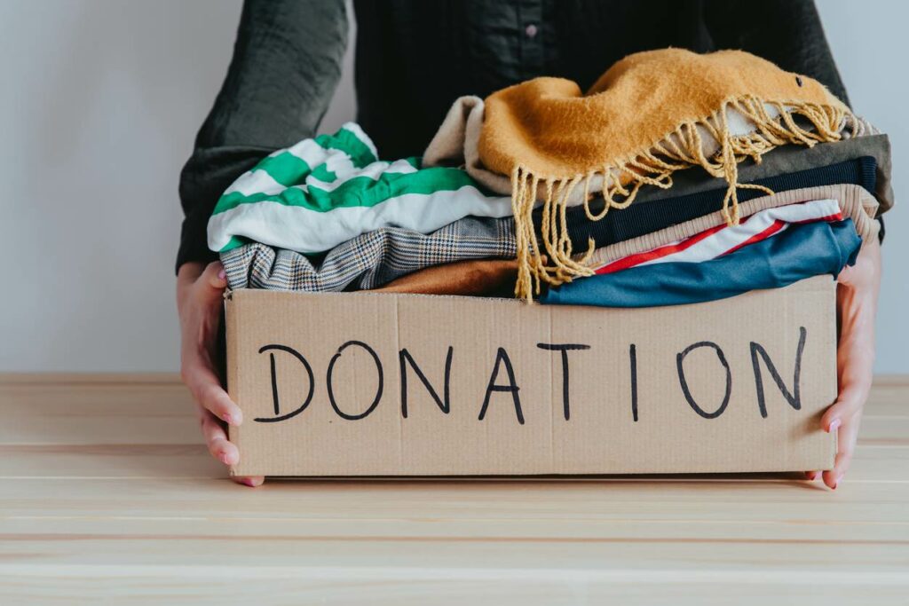 A woman holds a box of clothes labeled “Donation.”