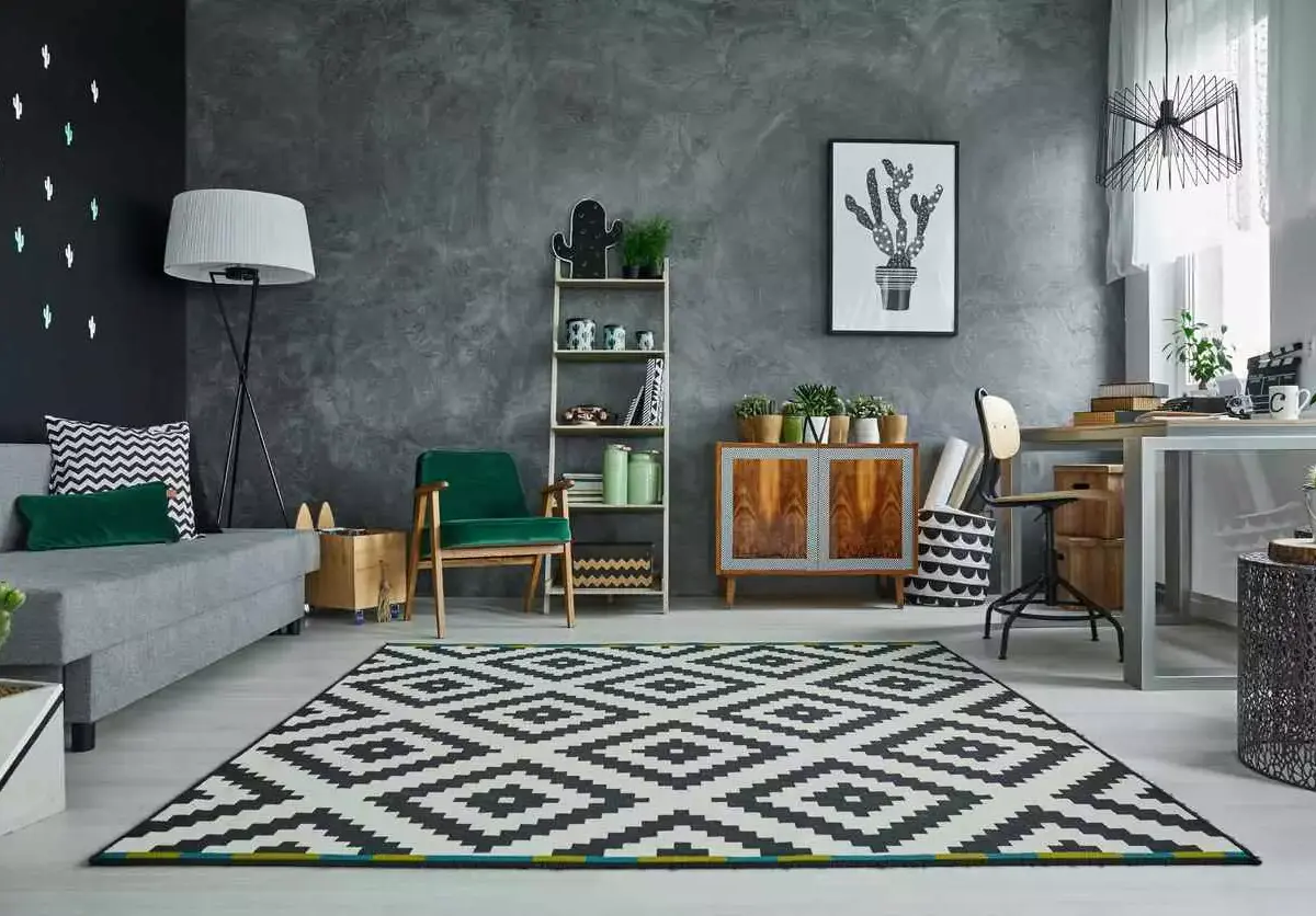 A brightly lit, clean room features a couch, shelves, and work desk