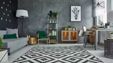 A brightly lit, clean room features a couch, shelves, and work desk