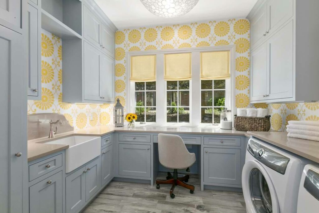 A padded rolling chair sits at a desk space surrounded by a sink and laundry area
