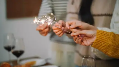 Group of friends celebrating new year’s with sparklers and food