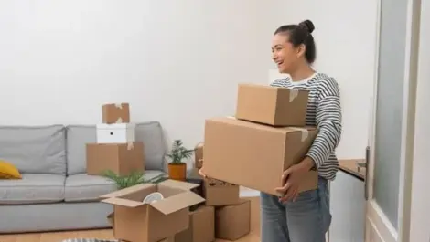 A woman holds boxes of things as she packs up and downsizes her home.
