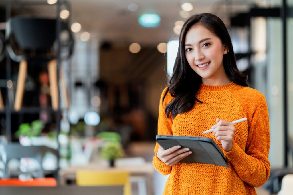 A young entrepreneur holding a tablet and standing in front of inventory.