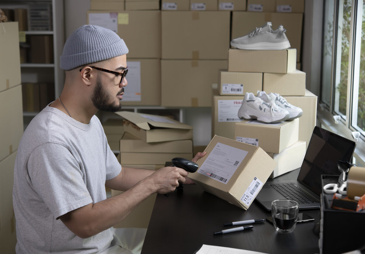 An entrepreneur labeling and scanning a box for e-commerce purchase.