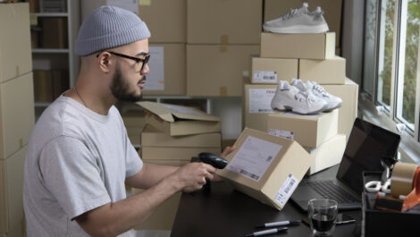 An entrepreneur labeling and scanning a box for e-commerce purchase.