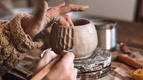 A woman etches into a clay bowl while working on her pottery.