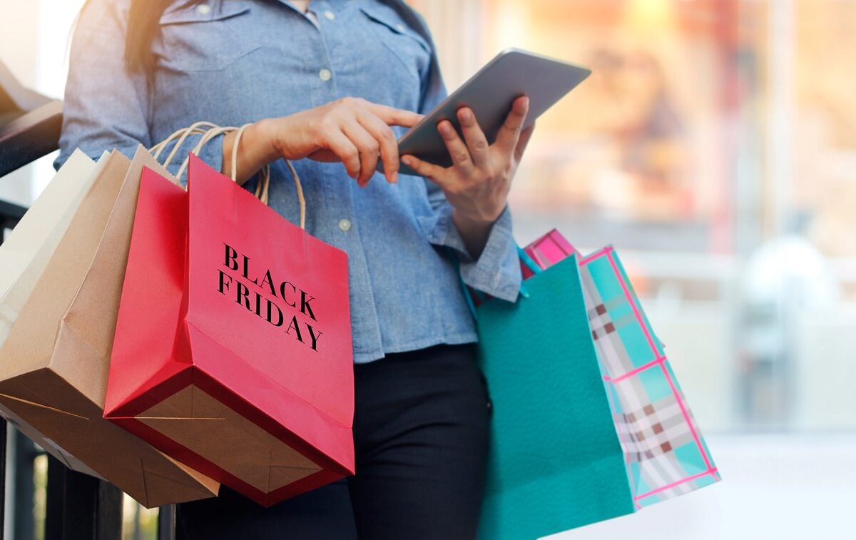 A woman holds various shopping bags while Black Friday shopping.