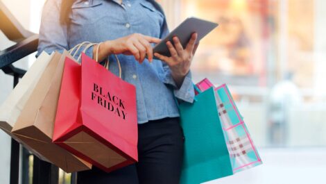 A woman holds various shopping bags while Black Friday shopping.