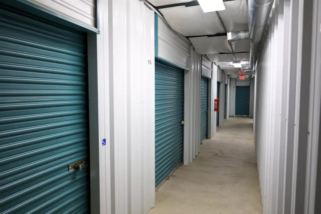 Hallway view of indoor storage units with teal doors.