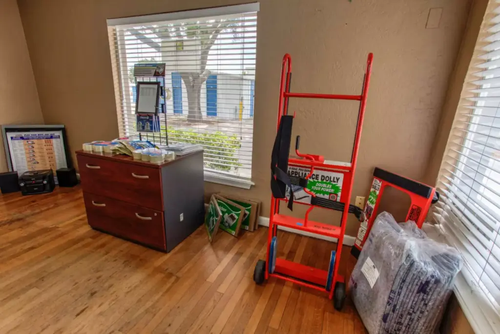 Dolly and moving supplies next to a dresser.