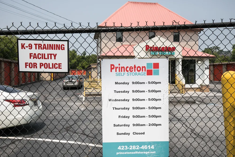 Fence with self storage hours sign.