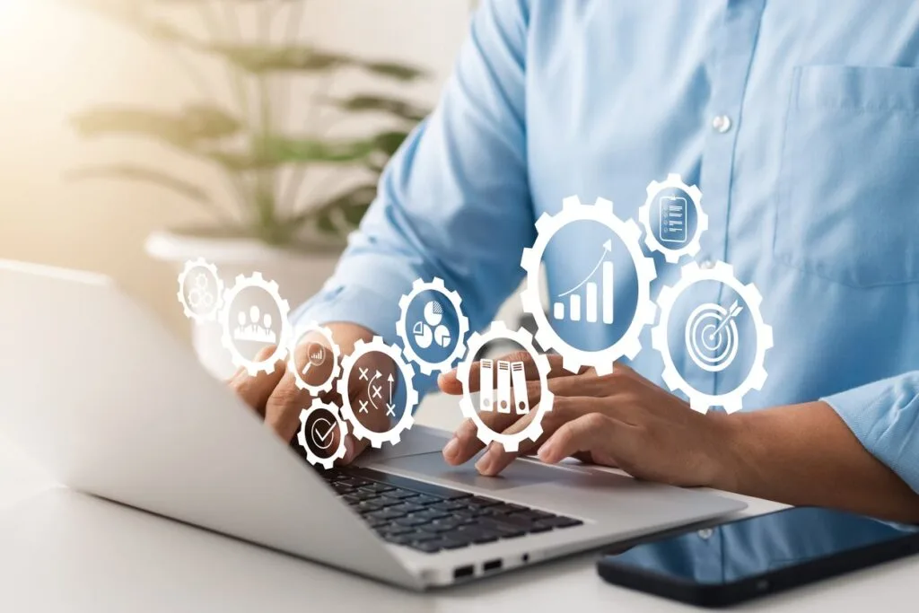 A graphic with a man typing on a laptop and gears floating around.