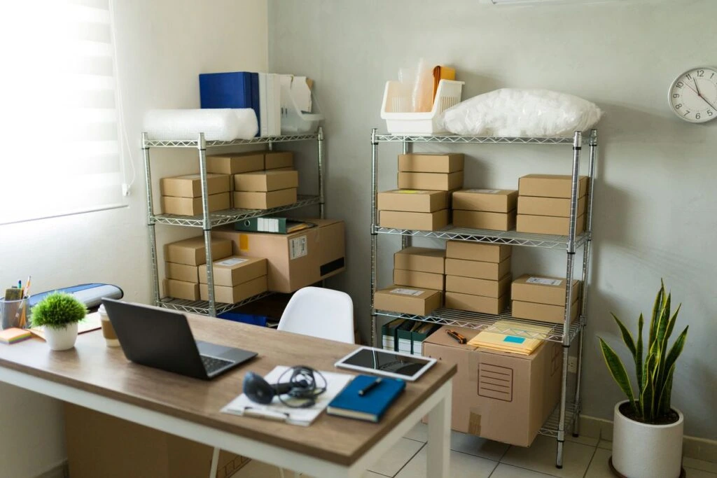 A cluttered office with brown inventory boxes stacked on shelves.