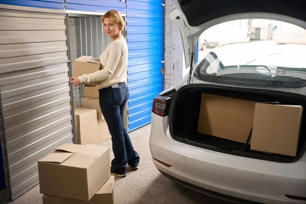 A woman unloading boxes from a car into a self-storage unit.