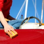 Someone in a red shirt polishing the bow of their boat.