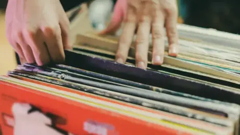 A person flipping through a stack of vinyl records.