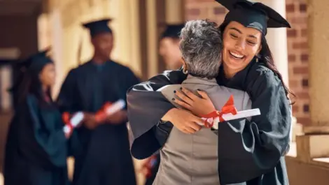 A female graduate hugging a loved one after walking.